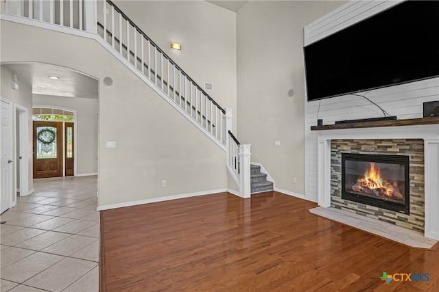 unfurnished living room with a fireplace, wood-type flooring, and a high ceiling