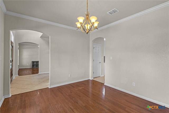 empty room with light hardwood / wood-style floors, ornamental molding, and an inviting chandelier