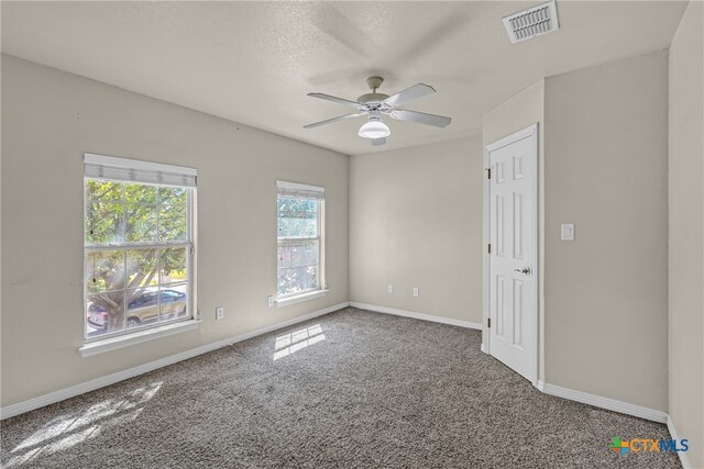 carpeted empty room featuring ceiling fan and a textured ceiling