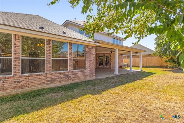 rear view of property with ceiling fan, a yard, and a patio