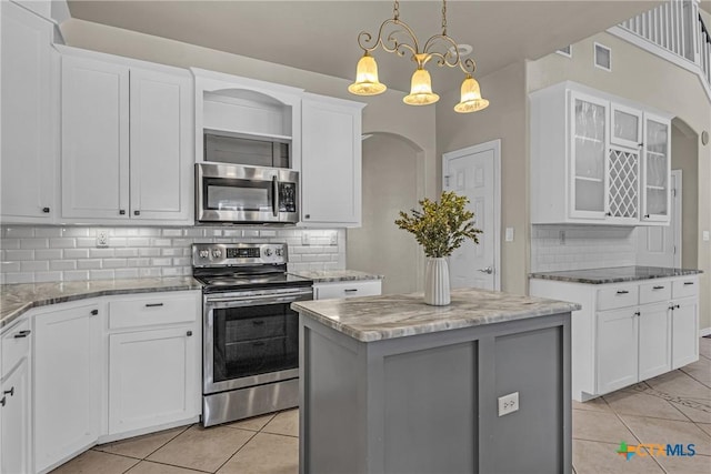 kitchen featuring white cabinets, appliances with stainless steel finishes, a center island, and decorative backsplash