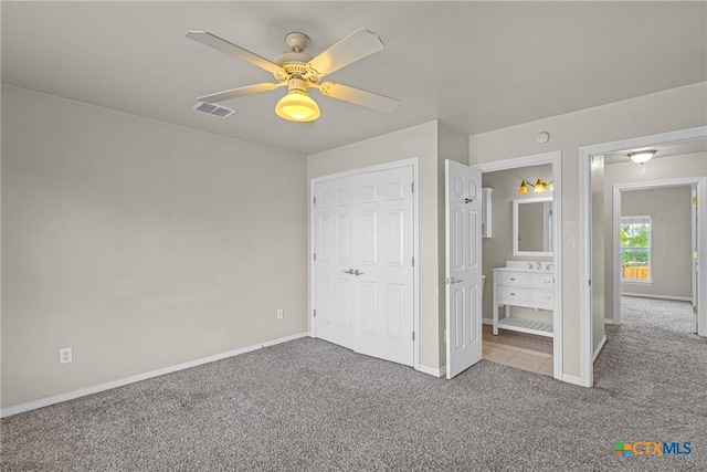 unfurnished bedroom with connected bathroom, light carpet, a closet, and ceiling fan