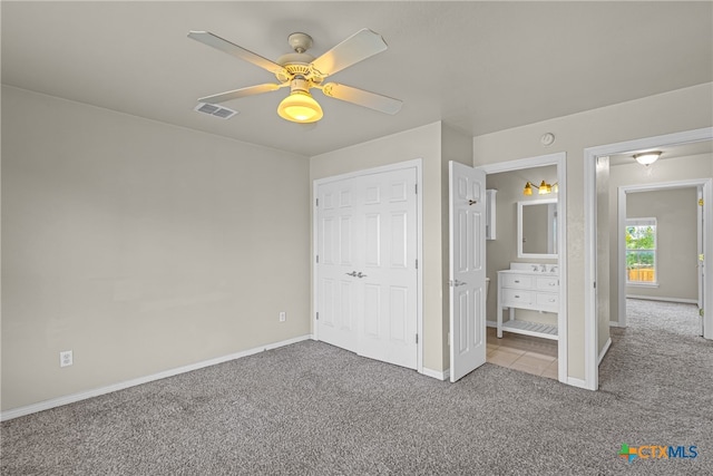 unfurnished bedroom featuring connected bathroom, ceiling fan, a closet, and light colored carpet