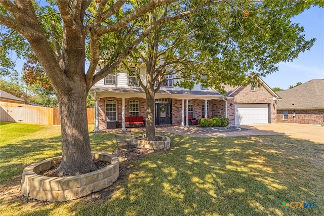 view of front of house with a garage, covered porch, and a front lawn