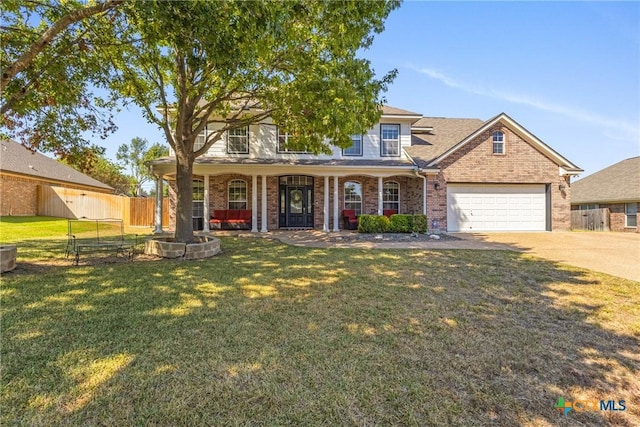 view of front of property with covered porch, a front yard, and a garage