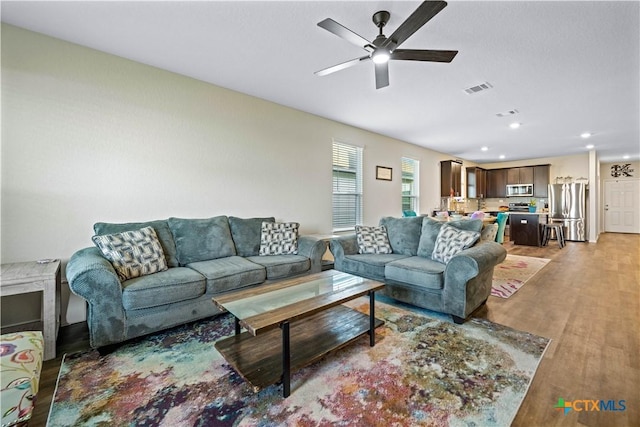 living room featuring wood-type flooring and ceiling fan