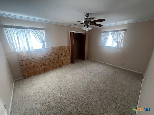 unfurnished bedroom with ornamental molding, a ceiling fan, a closet, carpet flooring, and baseboards