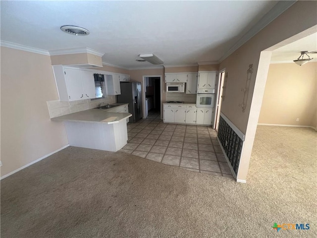 kitchen with light carpet, a peninsula, white appliances, white cabinetry, and a sink