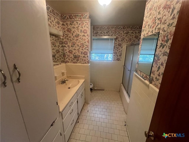 bathroom with wallpapered walls, tile patterned floors, toilet, and a wainscoted wall