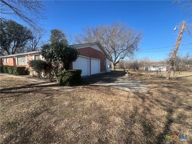 view of property exterior featuring brick siding, driveway, and an attached garage