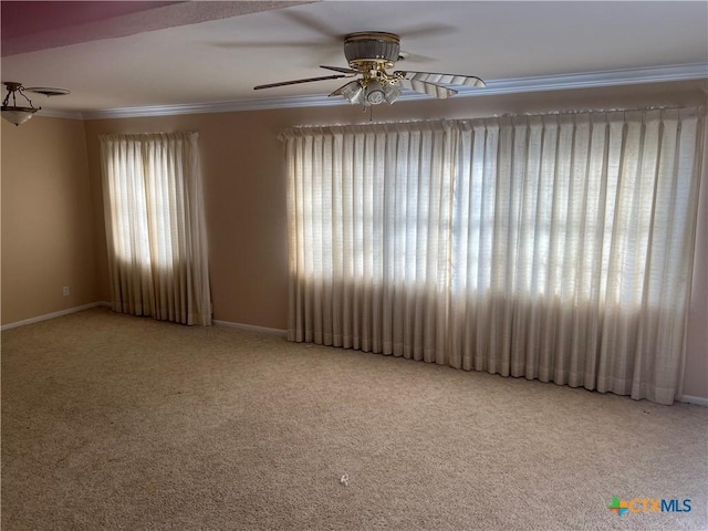 carpeted spare room featuring crown molding, a ceiling fan, and baseboards