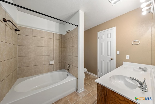 full bathroom featuring vanity, tile patterned flooring, tiled shower / bath, and toilet