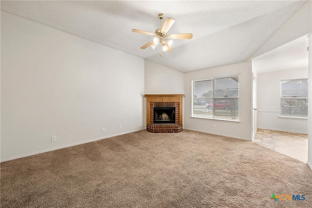 unfurnished living room with ceiling fan, a brick fireplace, carpet floors, a textured ceiling, and lofted ceiling