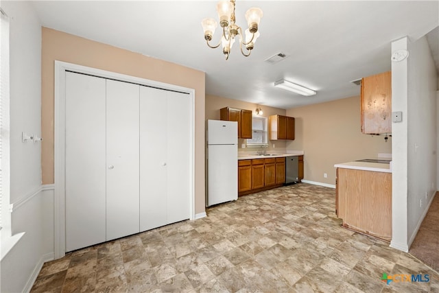 kitchen with sink, an inviting chandelier, dishwasher, white fridge, and hanging light fixtures