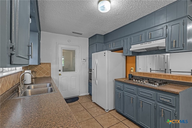 kitchen with stainless steel appliances, sink, tasteful backsplash, a textured ceiling, and light tile patterned floors