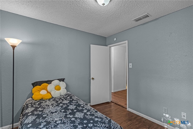 bedroom with dark wood-type flooring and a textured ceiling