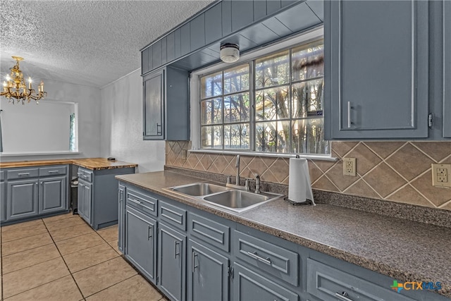 kitchen with light tile patterned floors, a textured ceiling, sink, and backsplash