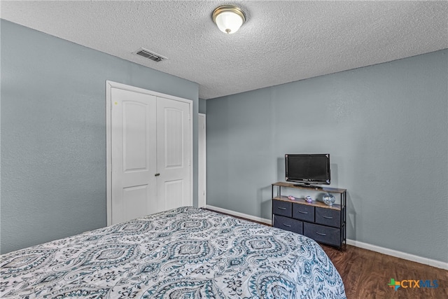 bedroom featuring dark wood-type flooring, a textured ceiling, and a closet