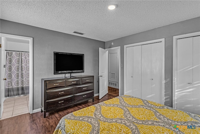 bedroom featuring a textured ceiling, two closets, and dark hardwood / wood-style floors