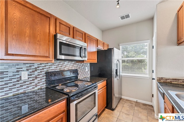 kitchen featuring backsplash, sink, light tile patterned flooring, and stainless steel appliances