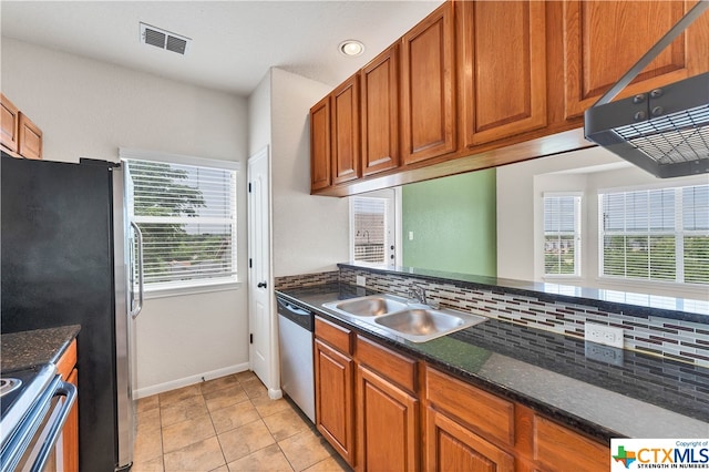 kitchen featuring light tile patterned flooring, sink, appliances with stainless steel finishes, dark stone countertops, and decorative backsplash