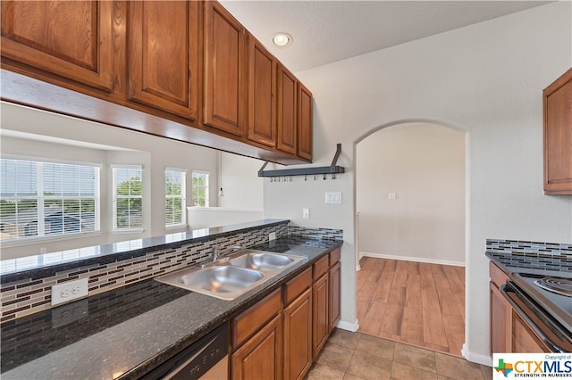 kitchen featuring sink, tasteful backsplash, dark stone countertops, light hardwood / wood-style flooring, and dishwasher