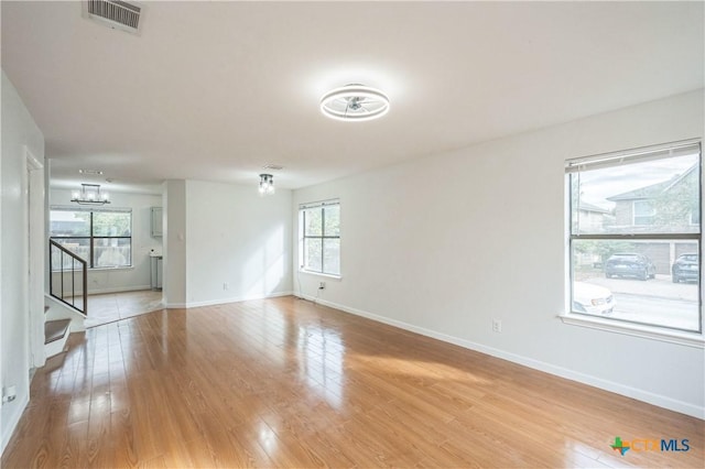 empty room with a chandelier and light hardwood / wood-style floors