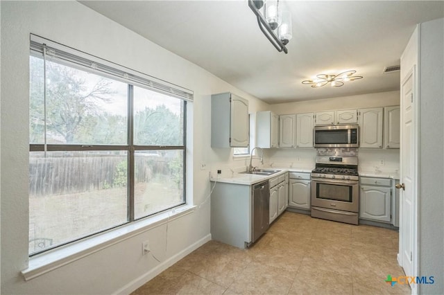 kitchen featuring gray cabinets, sink, stainless steel appliances, and tasteful backsplash