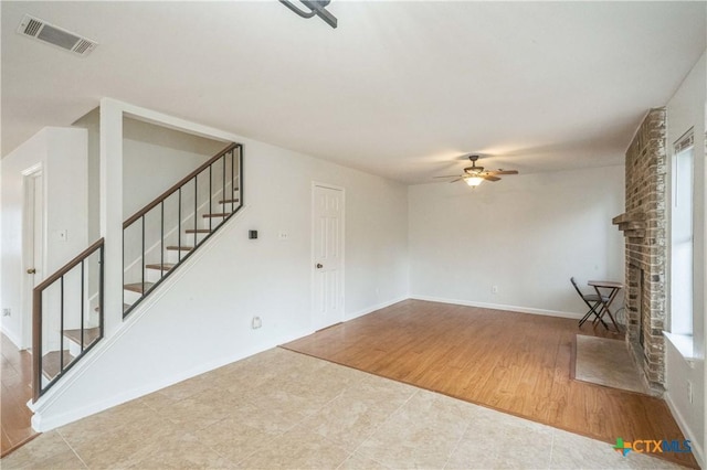 unfurnished living room featuring a fireplace, light hardwood / wood-style floors, and ceiling fan