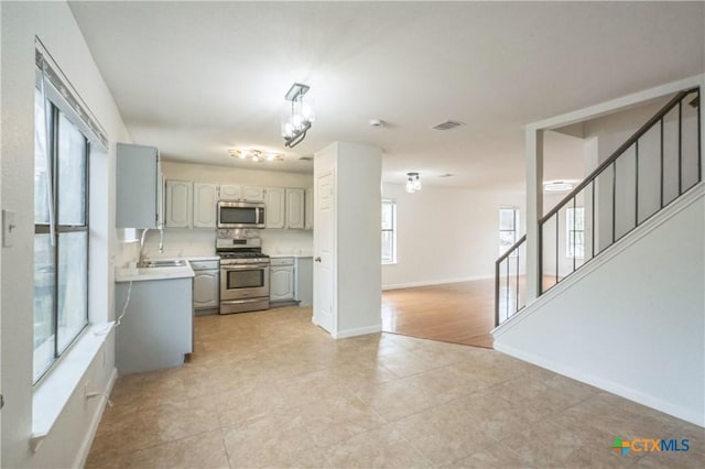 kitchen with decorative backsplash, gray cabinetry, stainless steel appliances, sink, and light tile patterned floors