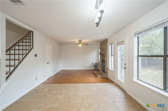 interior space featuring a fireplace, light tile patterned floors, and ceiling fan