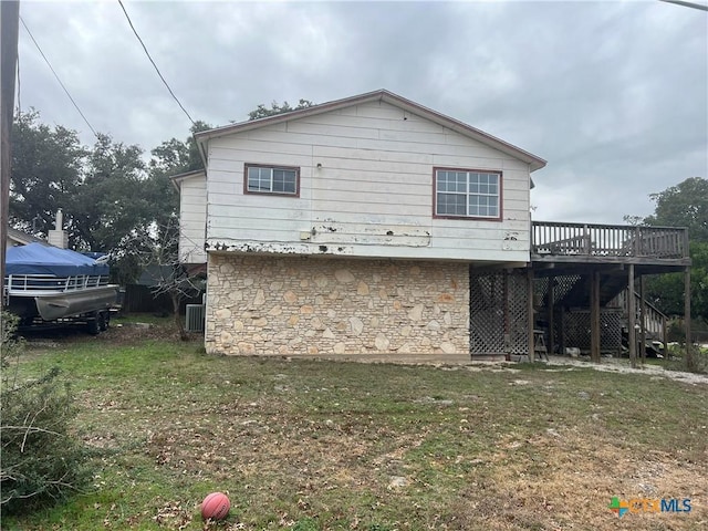 back of property featuring a deck, cooling unit, and a lawn