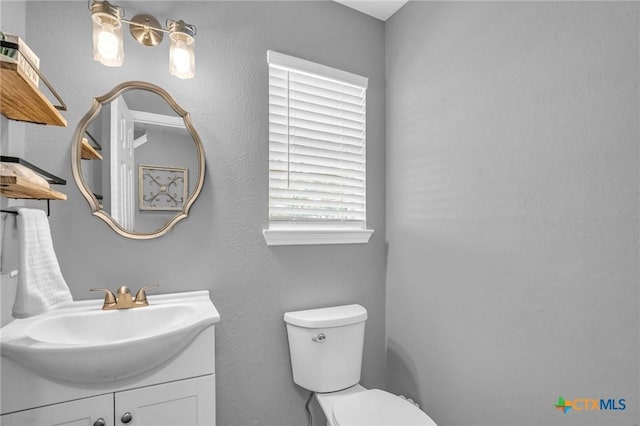 half bath featuring vanity and toilet