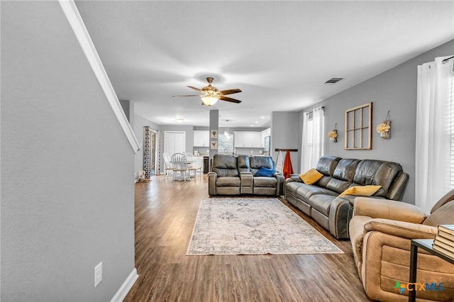 living area with baseboards, a ceiling fan, wood finished floors, and visible vents