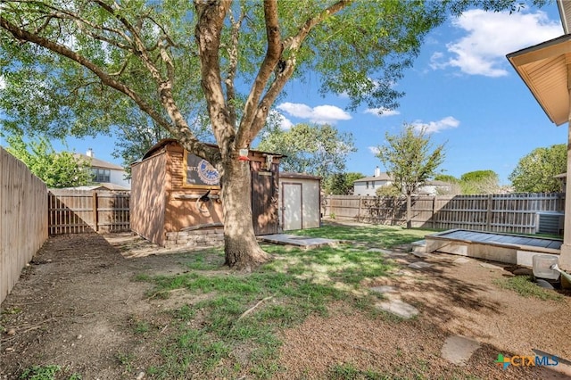 view of yard featuring a fenced backyard, a storage unit, and an outbuilding