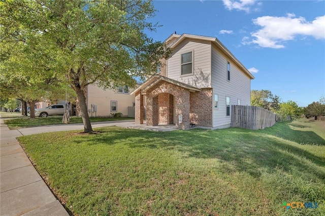 traditional home with brick siding, driveway, a front lawn, and fence