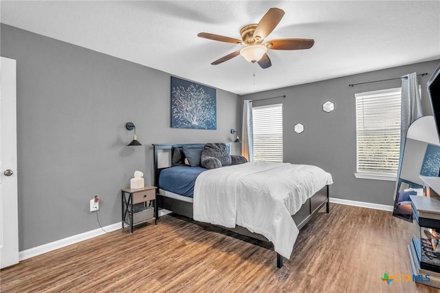 bedroom featuring baseboards, wood finished floors, and ceiling fan