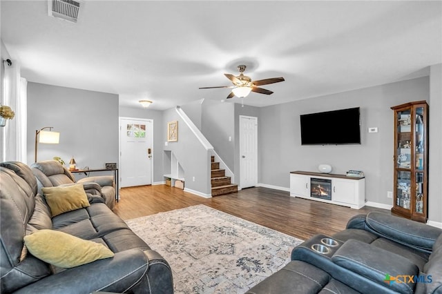 living area with baseboards, visible vents, a ceiling fan, wood finished floors, and stairs