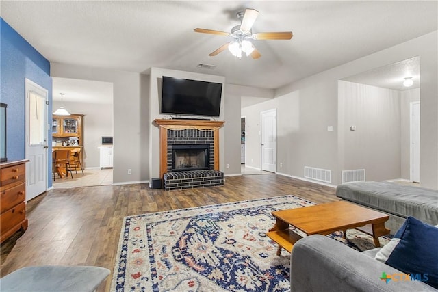 living room featuring ceiling fan, wood-type flooring, and a fireplace