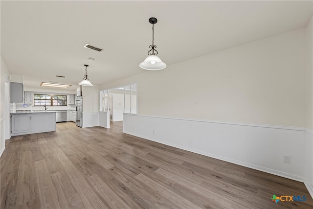 unfurnished living room featuring sink and light hardwood / wood-style flooring