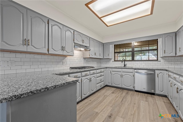 kitchen with stainless steel appliances, sink, light hardwood / wood-style flooring, and backsplash