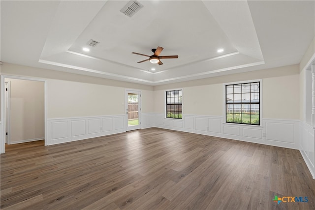 unfurnished room with a wealth of natural light, dark hardwood / wood-style floors, and a raised ceiling