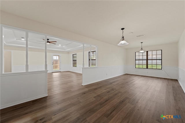 empty room with ceiling fan, a raised ceiling, and dark hardwood / wood-style flooring