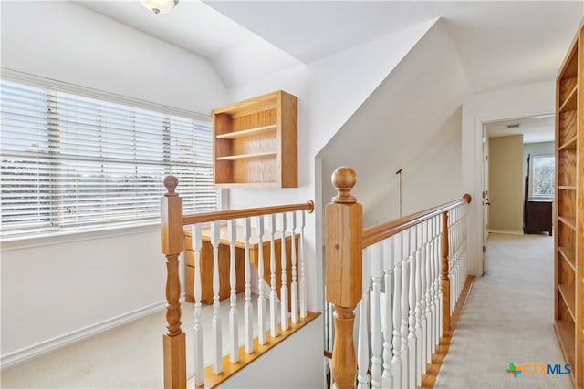 hallway with light colored carpet and vaulted ceiling