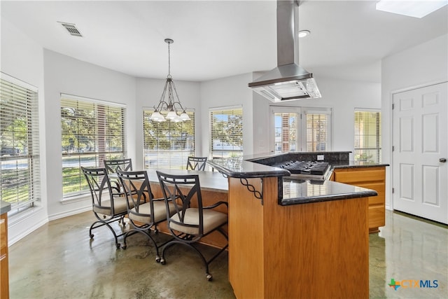 kitchen featuring island exhaust hood, concrete floors, pendant lighting, and kitchen peninsula