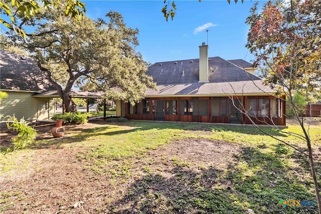 rear view of property featuring a sunroom and a yard