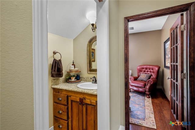 bathroom featuring vanity, hardwood / wood-style flooring, and lofted ceiling