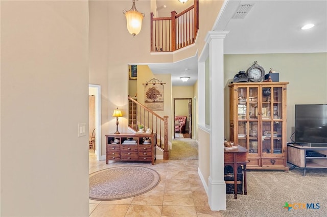 tiled entrance foyer featuring a towering ceiling and ornate columns