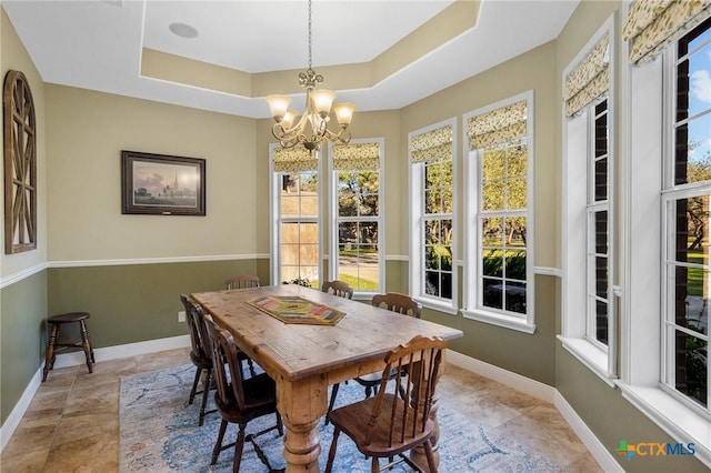 dining room with a chandelier and a raised ceiling