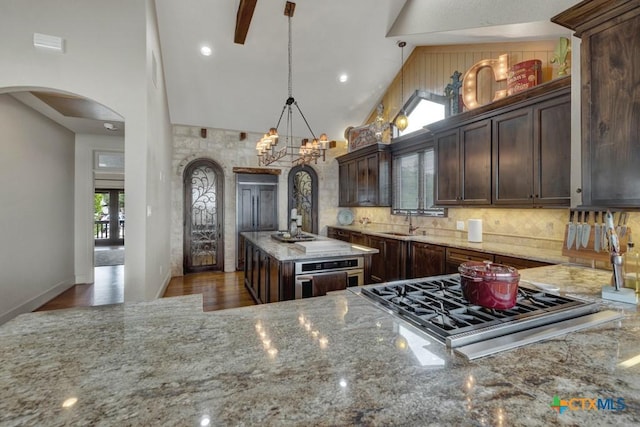 1746 Stagecoach Dr, Canyon Lake, TX 78133 - kitchen featuring arched walkways, appliances with stainless steel finishes, light stone counters, high vaulted ceiling, and decorative backsplash
